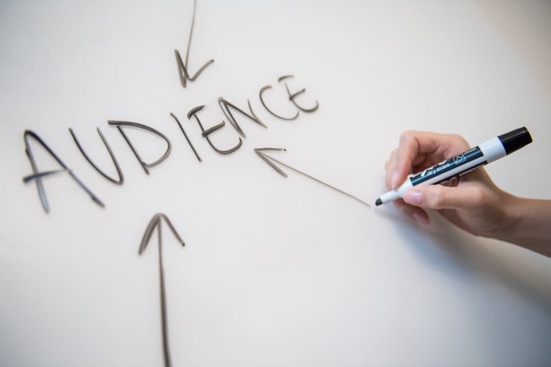 A person writing the keyword "audience" on a whiteboard.