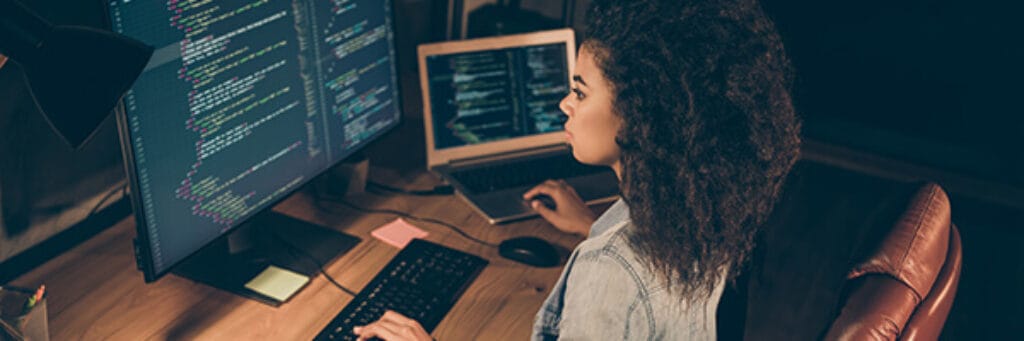 A woman analyzing code on a computer screen.