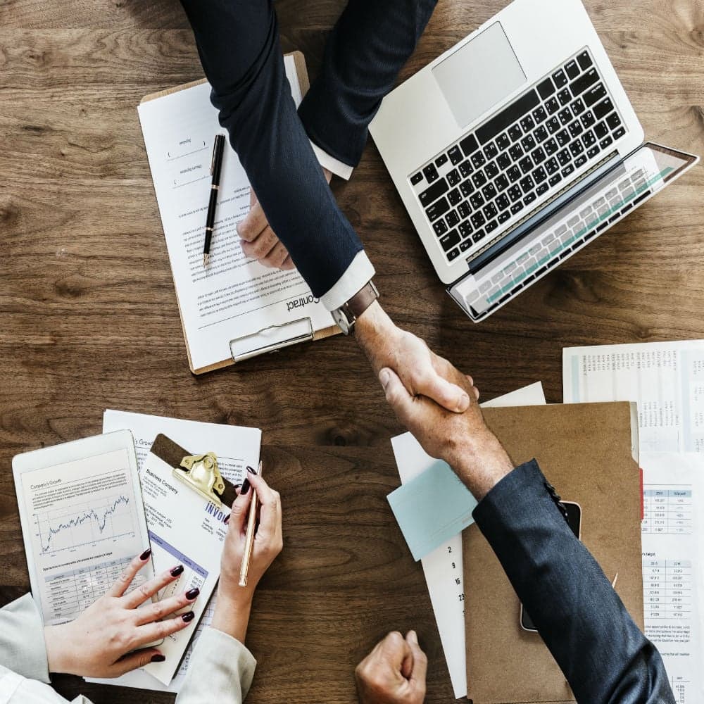 A group of business people shaking hands at a table.