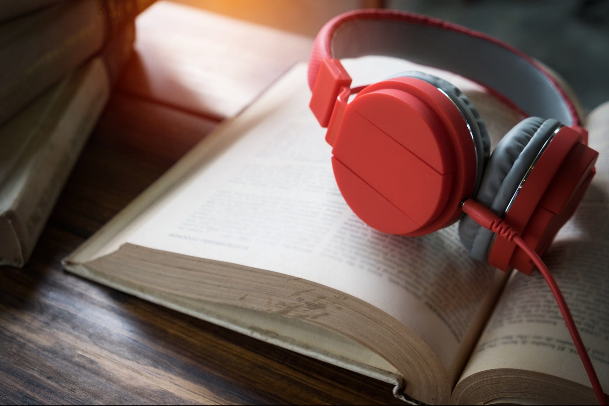 A pair of headphones resting on top of an open book featuring some of the best free audiobooks for entrepreneurs.