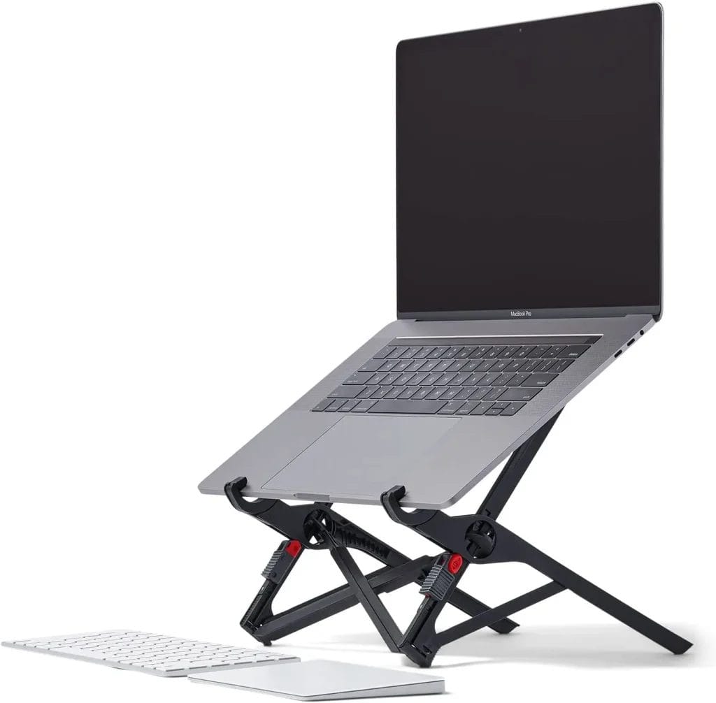 A laptop mounted on a black adjustable stand with an external keyboard placed in front of it.
