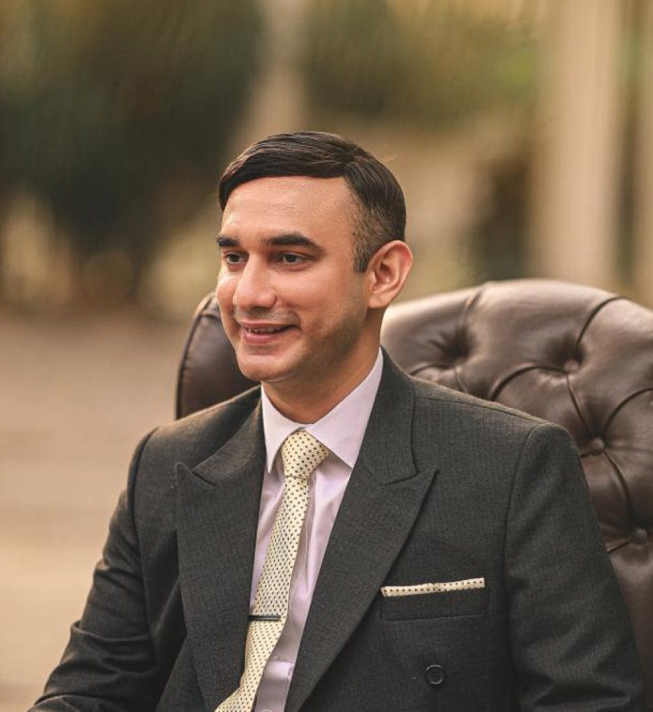 Muhammad Hamza Butt: man in a suit sitting in a leather armchair outdoors.