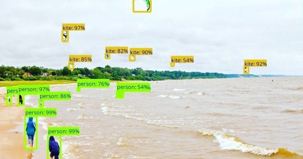 Beach scene with several people, possibly solopreneurs, walking along the shore and multiple kites flying above&mdash;each labeled with confidence percentages, illustrating the precision that top AI tools can bring to your daily workflow.
